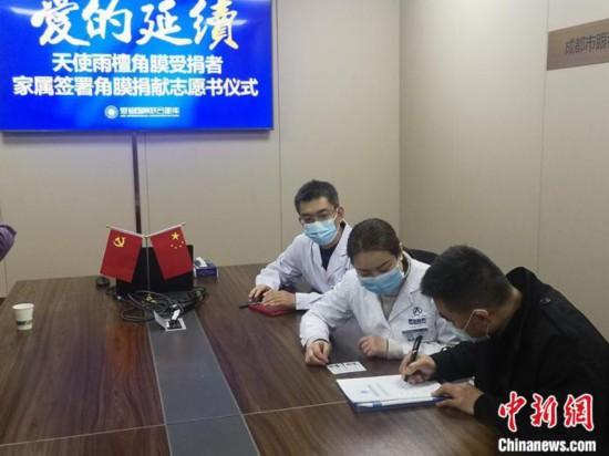 马先生(右)在捐献志愿书上签下自己名字。　杜成 摄