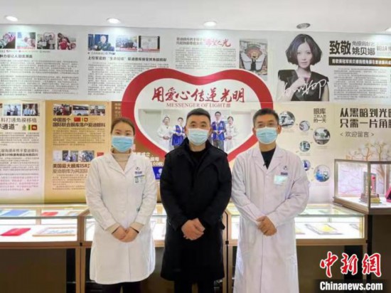 马先生(中)与医生在医院角膜捐赠墙前合影。　董倩 摄