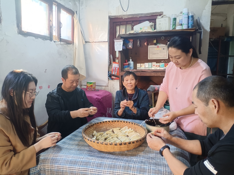 志愿者们与陈经霞（中）一起包饺子。