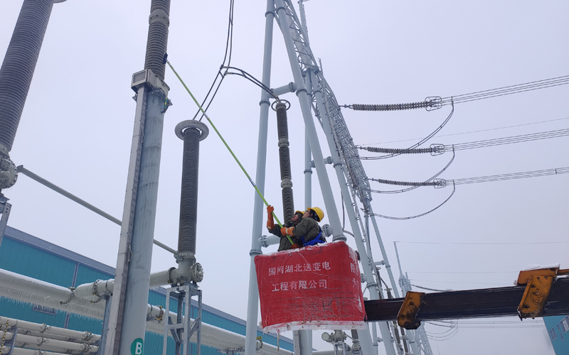 2月4日，特高压武汉换流变电站内，国网湖北送变电公司应急抢修人员手持除冰工具进行换流变进线区域电气设备的冰凌清理工作。蔡翔摄