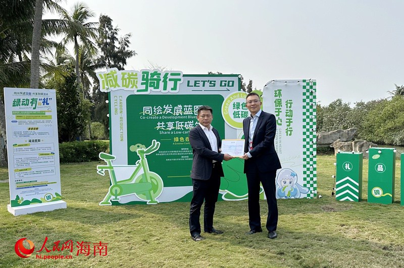 中共海南省委外事工作委员会办公室副主任王磊向琼海市人民政府副市长符展授予“碳汇捐赠感谢状”。人民网记者 符武平摄